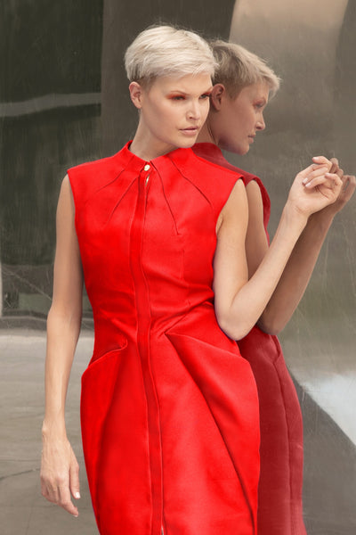 Midi red cocktail dress with gold tone zipper and adjustable front slit. Oragami style geometric design with inbuilt pockets 